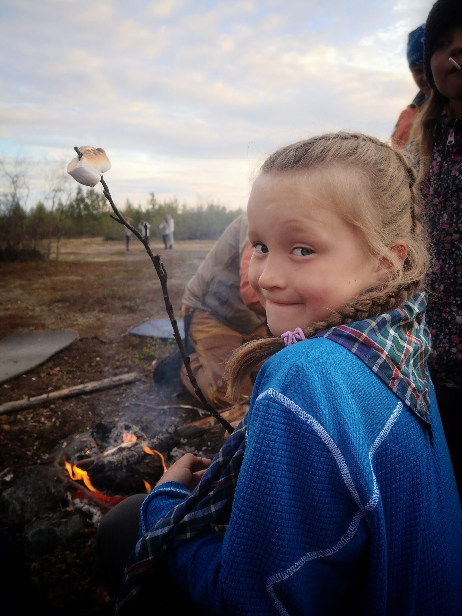 Jente ved bål med marshmallow på pinne