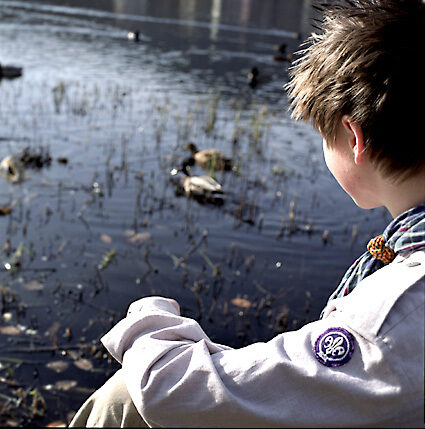 Speider sitter ved vann og ser utover