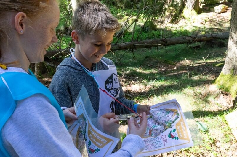 To speidere studerer kart og kompass ute i skogen