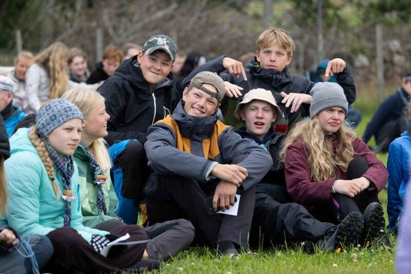Gruppe ungdommer sitter avslappet i gresset utendørs
