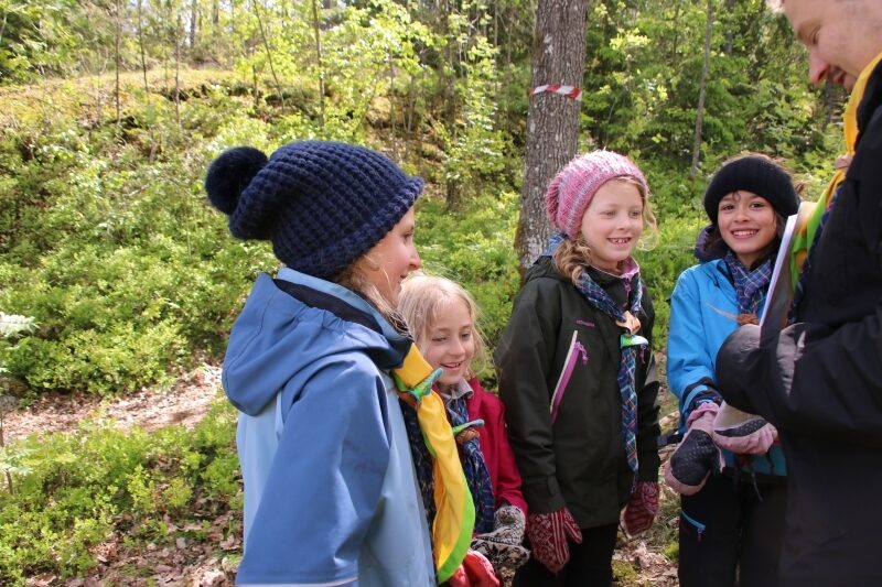Speidere som ser på et ark lederen holder og smiler.