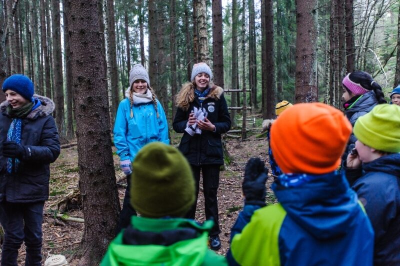 Speidere som står i ring og smiler i skogen
