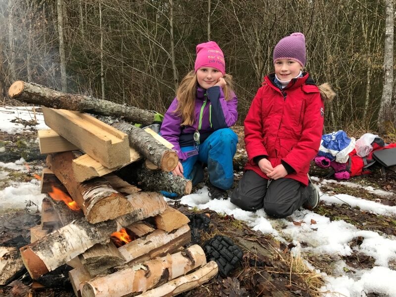 To speidere sitter ved et pagodebål i vinterlandskap