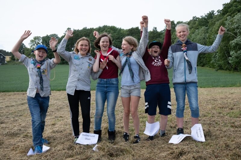 Speidere på et jorde som hopper av glede sammen