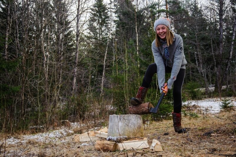 En speider som hugger ved på en huggestabbe i skogen