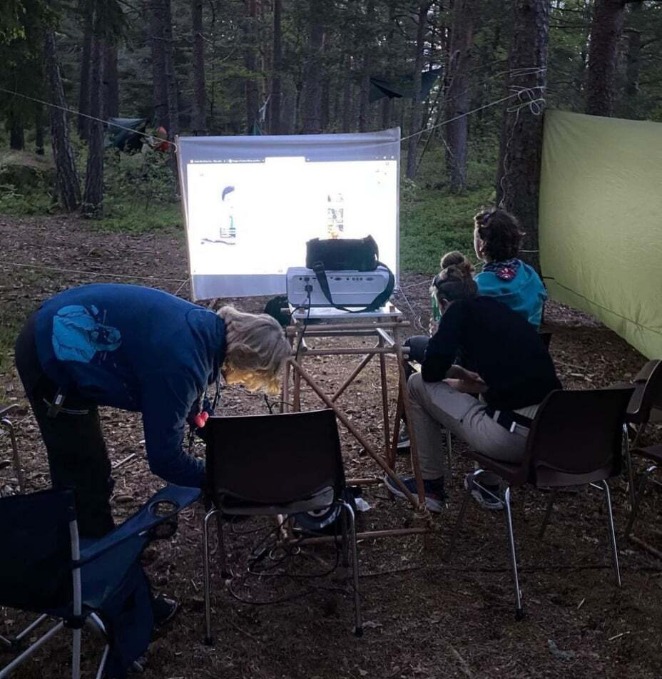 Rovere ser utekino i skogen med projektor og lerret